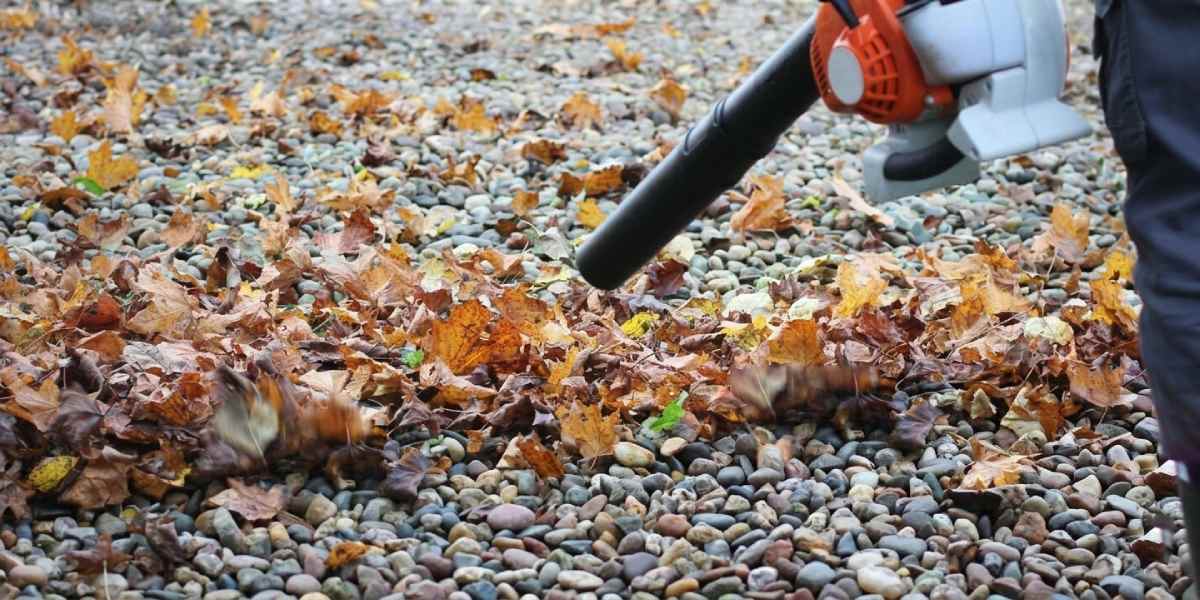 herfstbladeren worden weggeblazen van het grind met een bladblazer
